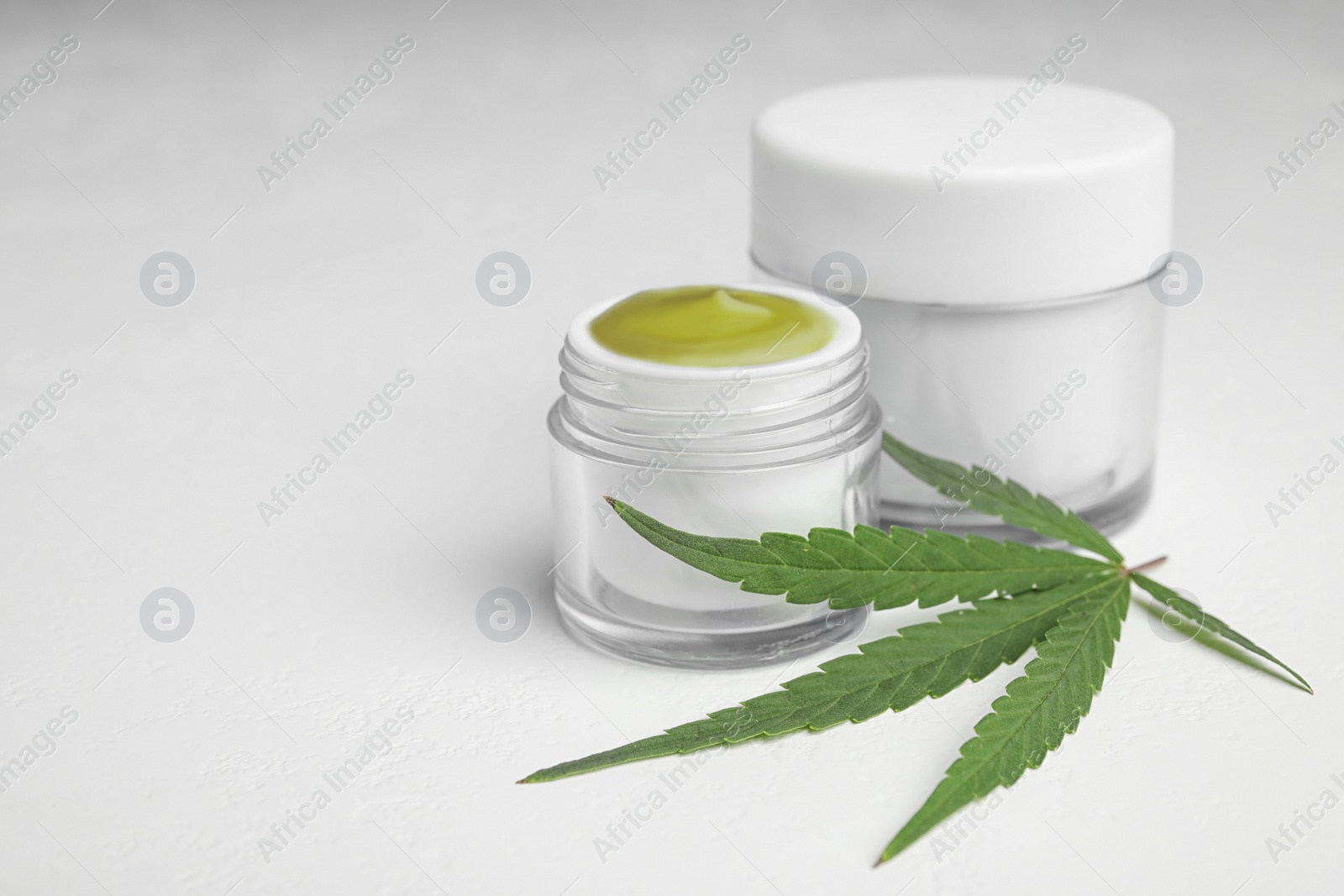 Photo of Jars of hemp cream on white table, space for text. Organic cosmetics