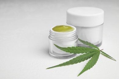 Jars of hemp cream on white table, space for text. Organic cosmetics