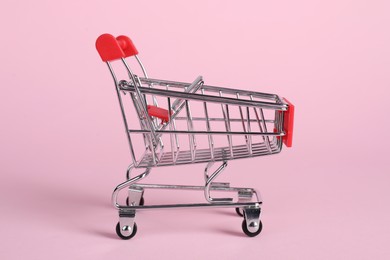 Photo of Small metal shopping cart on pink background