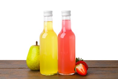 Delicious kombucha in glass bottles, strawberries and pear on wooden table against white background