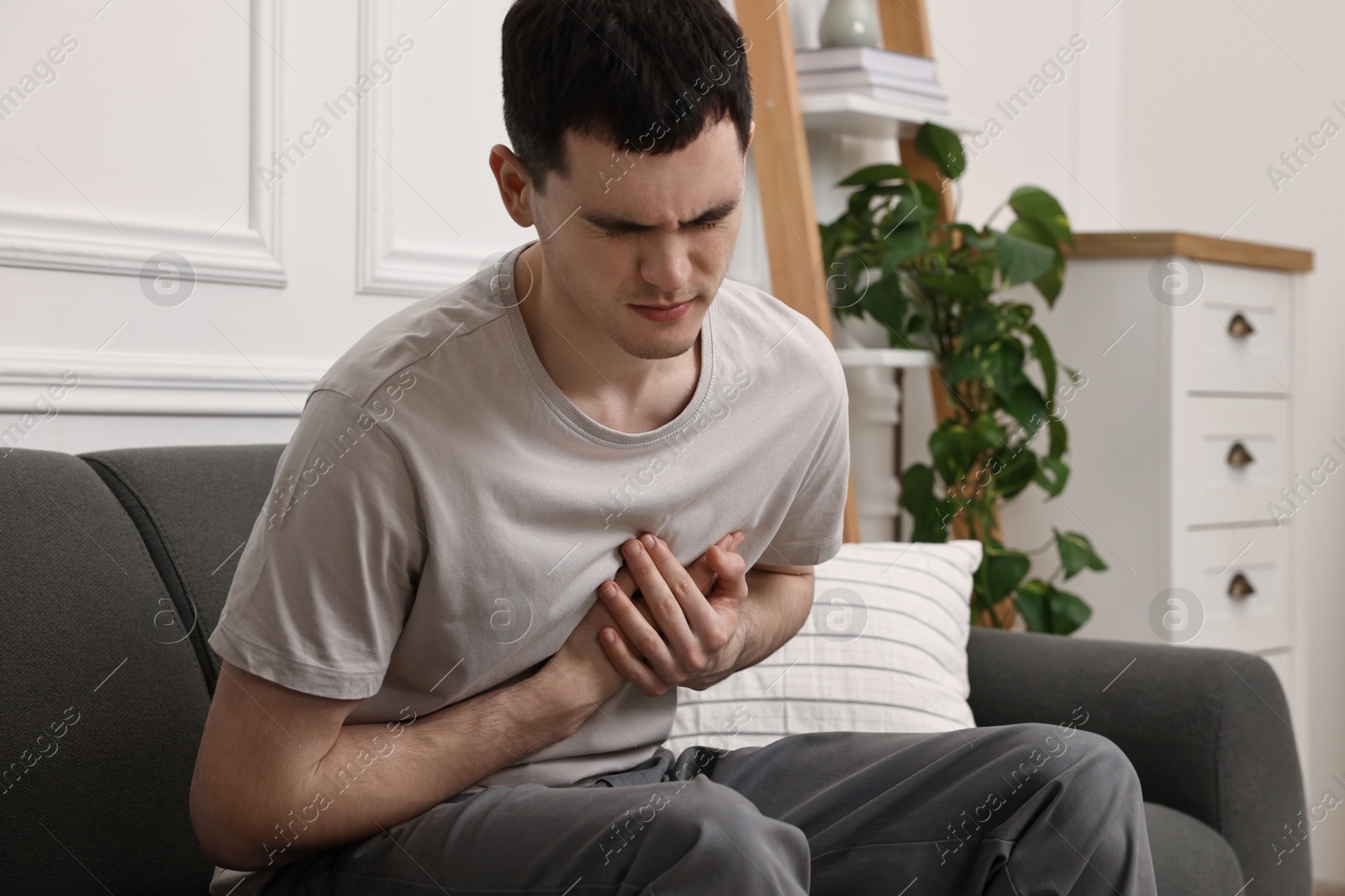 Photo of Young man suffering from heart hurt on sofa at home