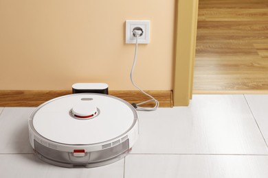 Robotic vacuum cleaner charging on white floor indoors