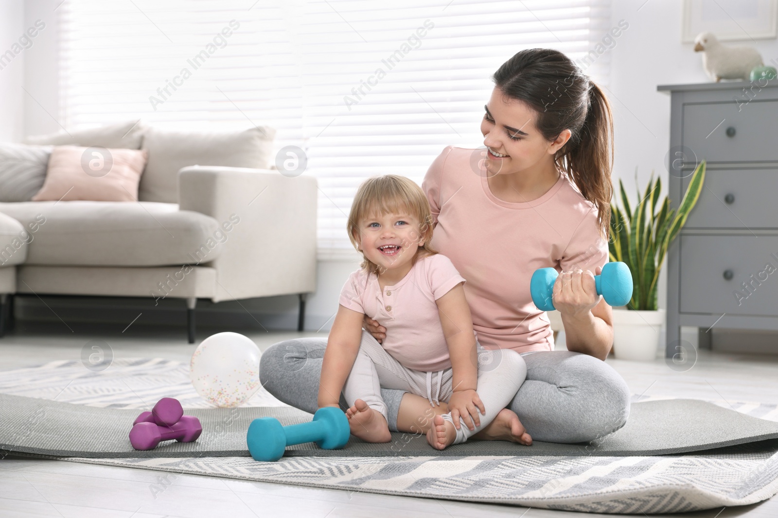 Photo of Mother and her daughter with dumbbells at home