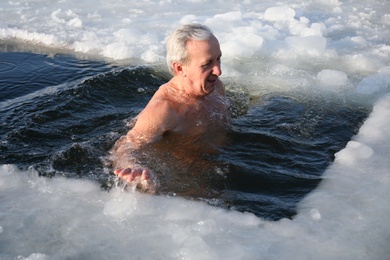 Photo of MYKOLAIV, UKRAINE - JANUARY 06, 2021: Mature man immersing in icy water on winter day