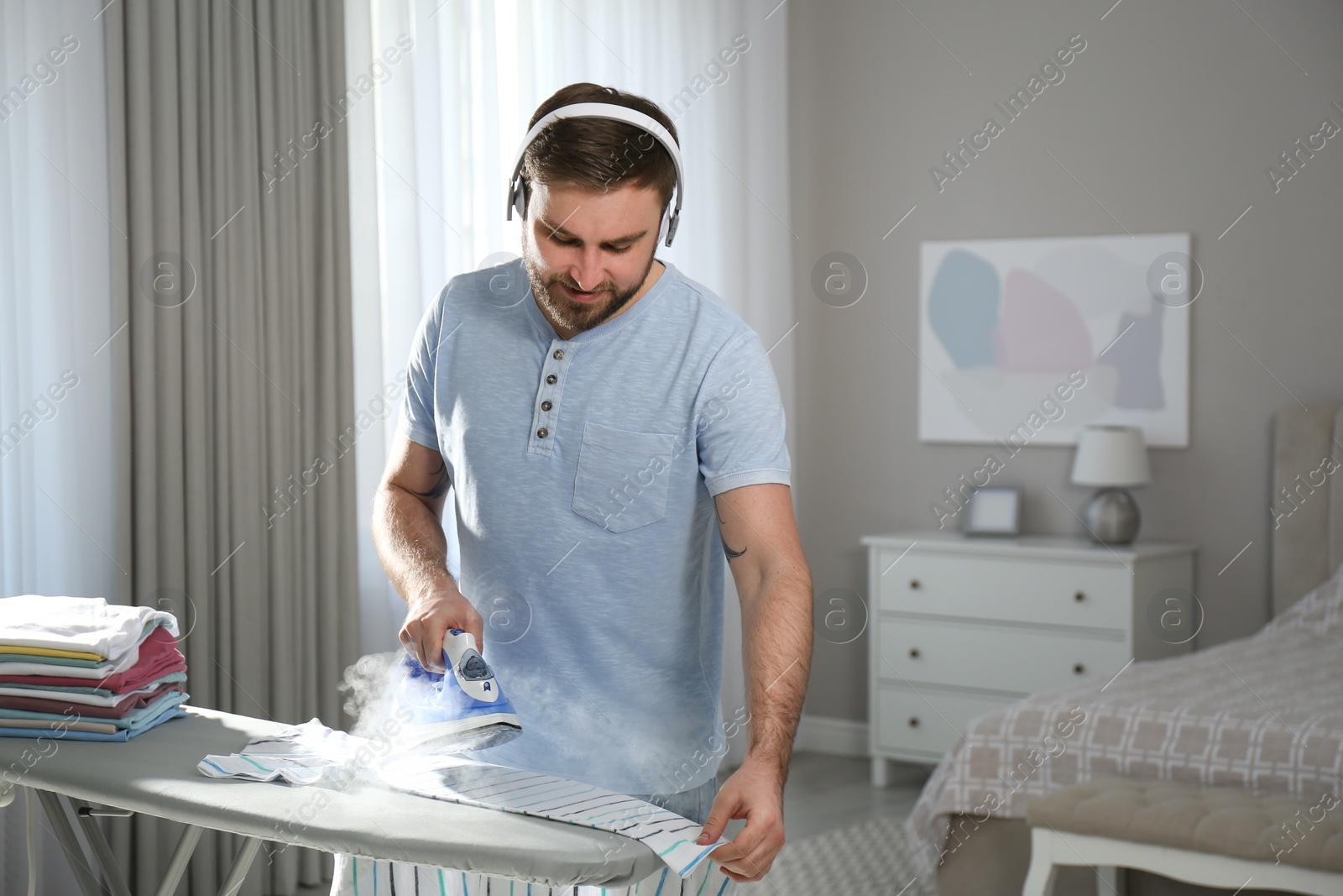Photo of Man listening to music while ironing at home