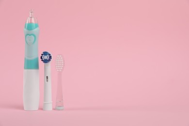 Electric toothbrush and replacement brush heads on pink background, space for text