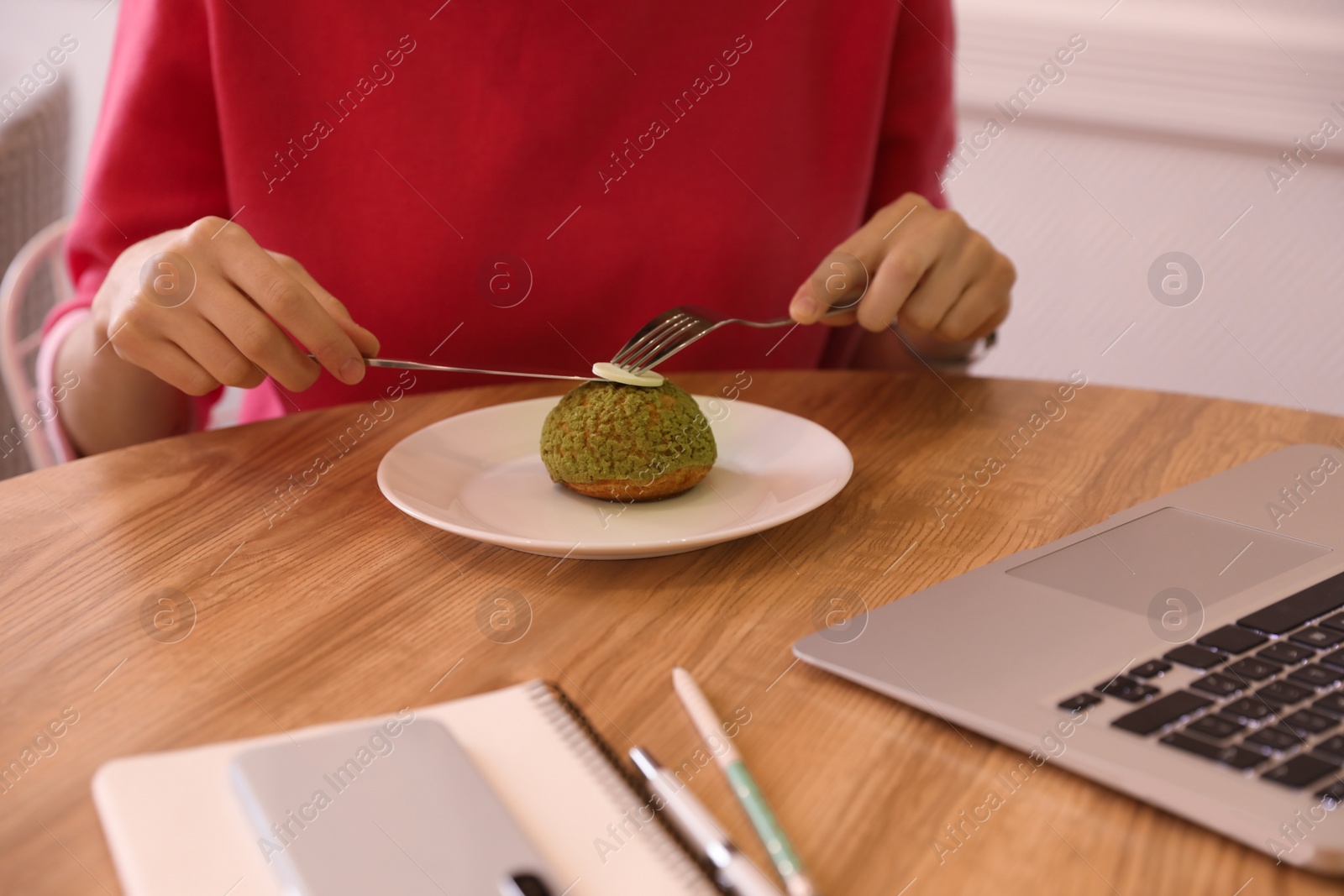 Photo of Young blogger eating dessert in cafe, closeup