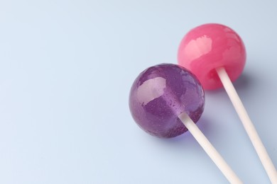 Tasty lollipops on light blue background, closeup. Space for text