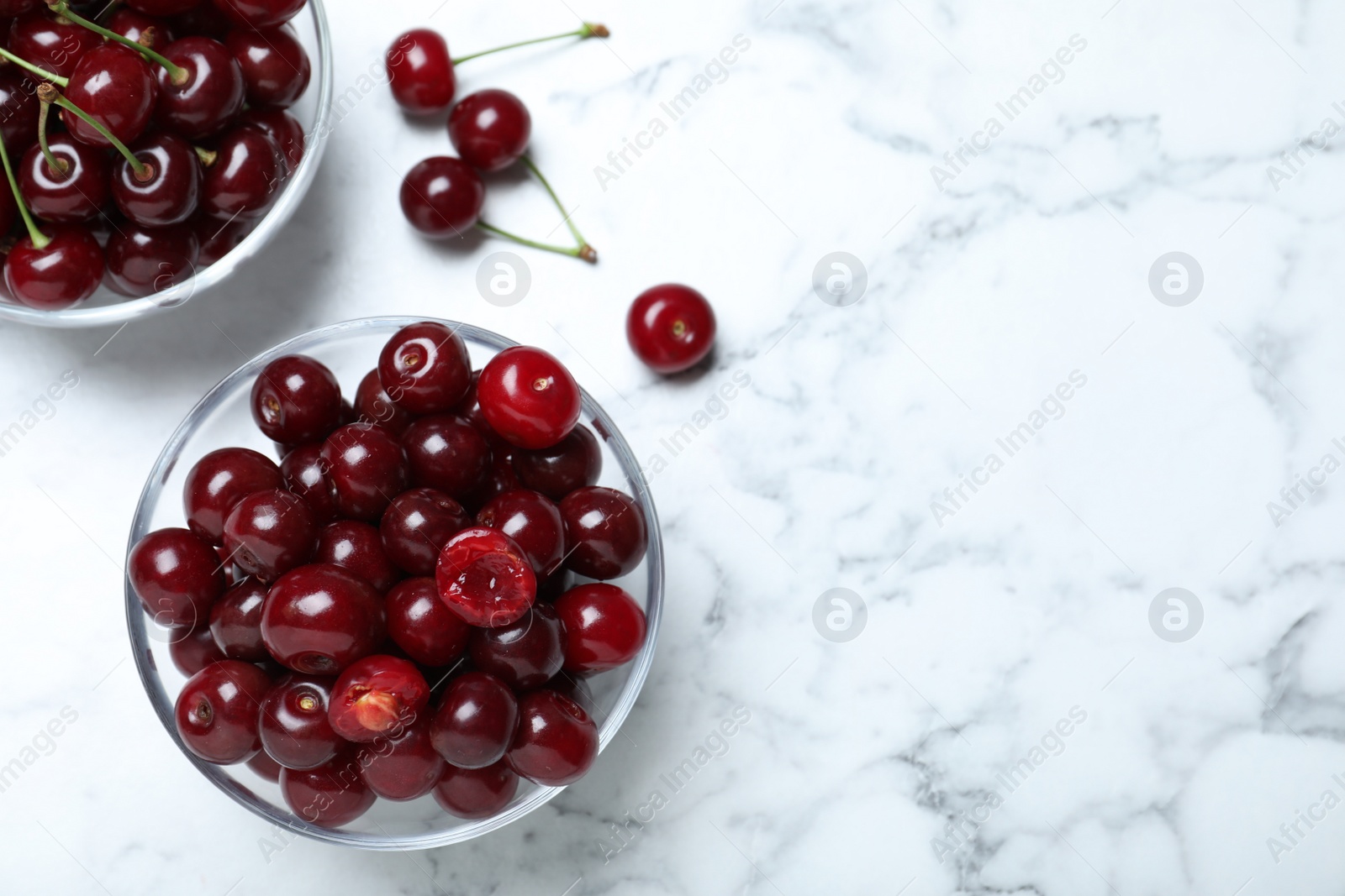 Photo of Sweet juicy cherries on white marble table, flat lay. Space for text