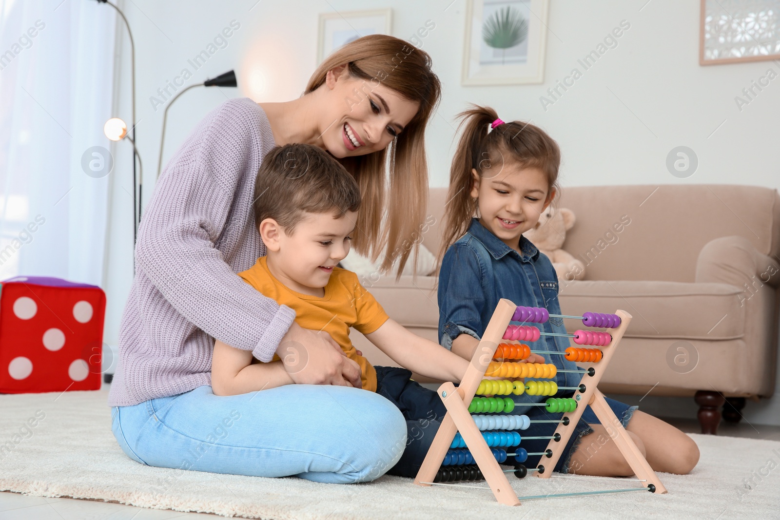 Photo of Nanny and little children playing with counting frame at home