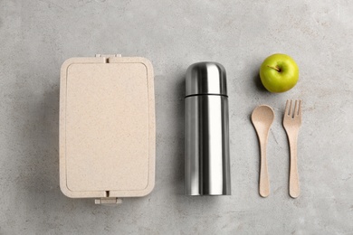 Photo of Thermos, lunch box and apple on light grey table, flat lay