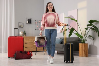 Travel with pet. Smiling woman holding carrier with dog and suitcase at home