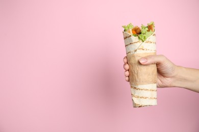 Photo of Woman holding delicious chicken shawarma on pink background, closeup. Space for text