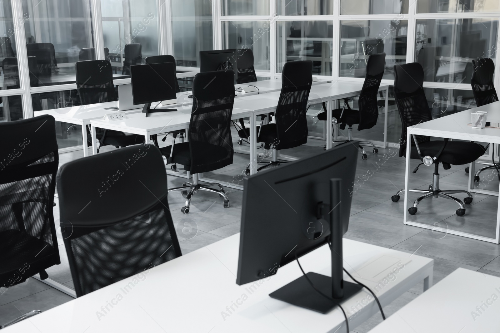 Photo of Stylish interior of open plan office. Workspace with computers, tables and chairs