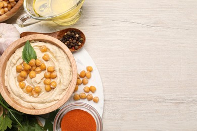 Photo of Delicious hummus with chickpeas and different ingredients on white wooden table, flat lay. Space for text