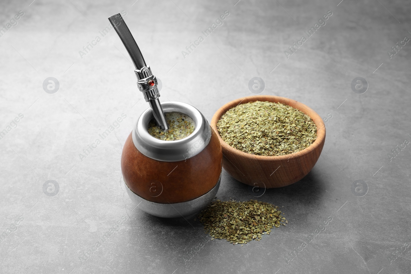 Photo of Calabash with bombilla and bowl of mate tea leaves on grey table