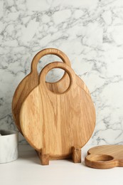 Photo of Wooden cutting boards on white table near marble wall
