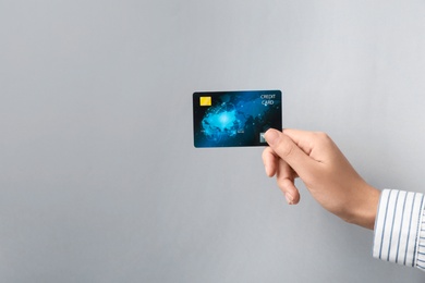 Woman holding credit card on light background