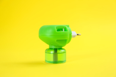 Photo of Electric vaporizer with insect repellent liquid on yellow background