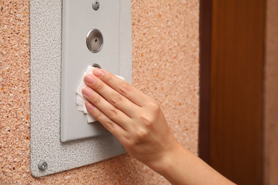 Photo of Woman using tissue paper to press elevator call button, closeup