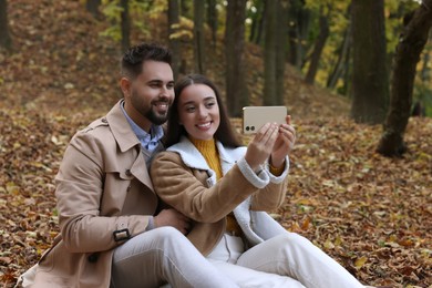 Photo of Happy young couple taking selfie in autumn park