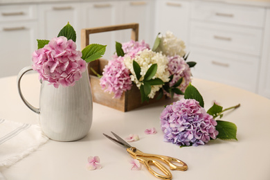 Beautiful hydrangea flowers and scissors on white table. Interior design element