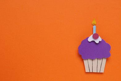 Photo of Birthday party. Paper cupcake on orange background, top view with space for text