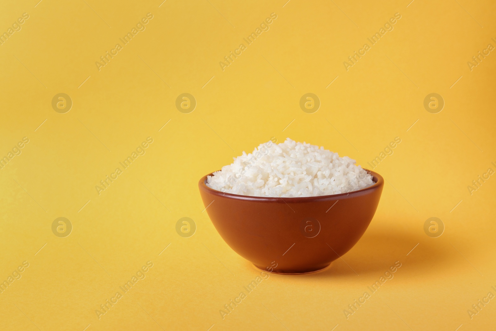 Photo of Bowl of boiled rice on color background. Space for text