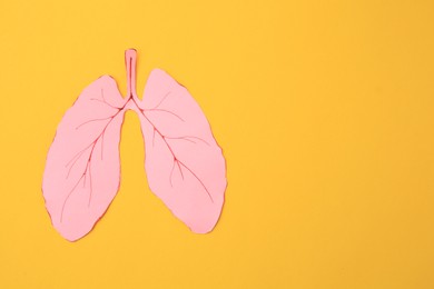 Paper cutout of human lungs on orange background, top view. Space for text