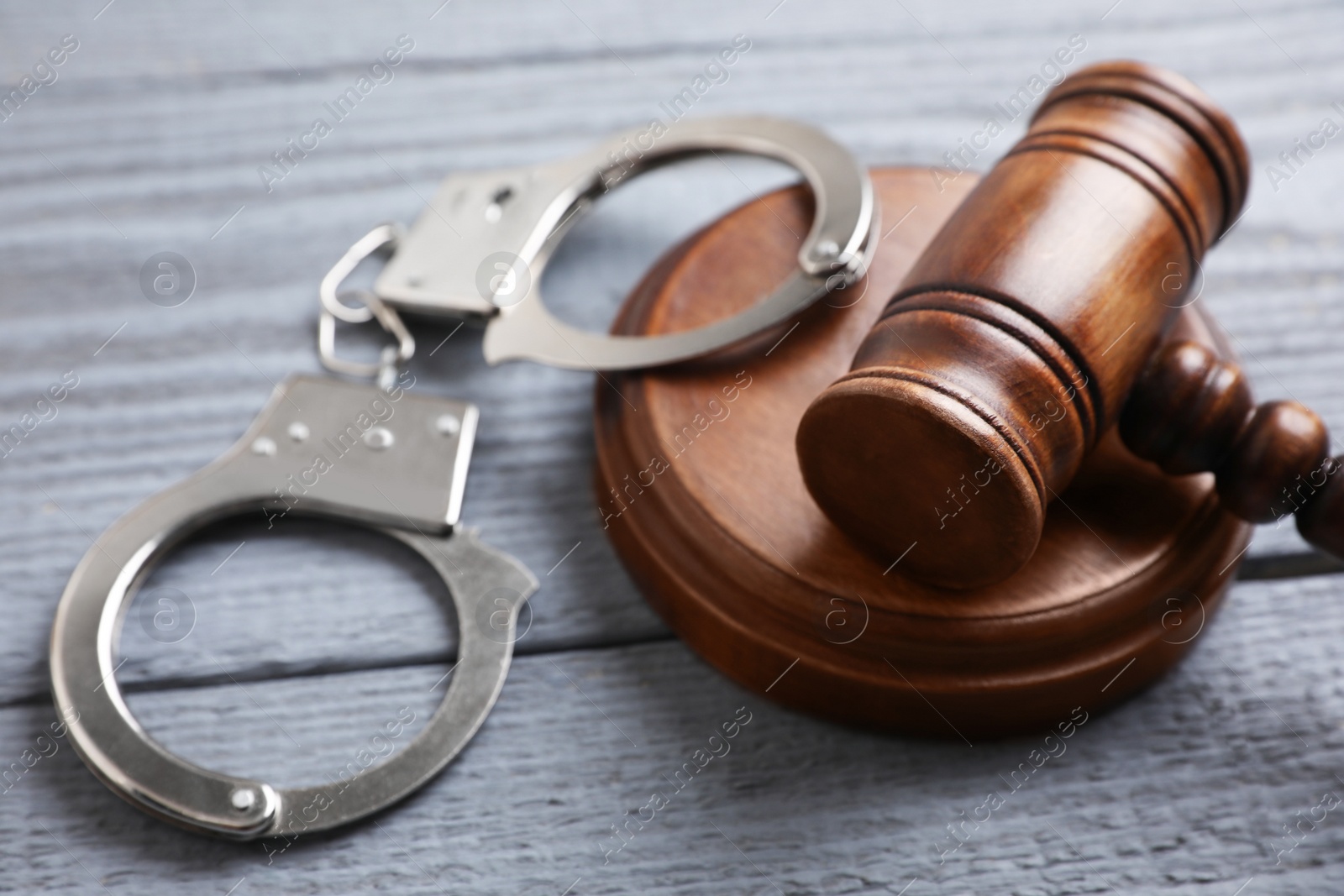 Photo of Gavel and handcuffs on grey wooden table, closeup. Criminal law