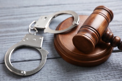 Photo of Gavel and handcuffs on grey wooden table, closeup. Criminal law