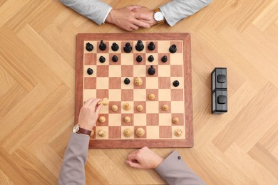 Photo of Men playing chess during tournament at wooden table, top view