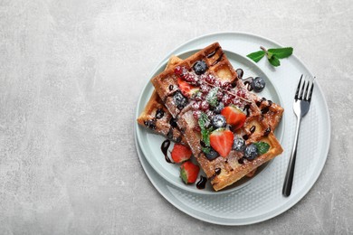 Photo of Delicious Belgian waffles with berries served on light grey table, top view. Space for text