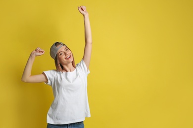 Photo of Young woman wearing blank t-shirt on yellow background. Mockup for design