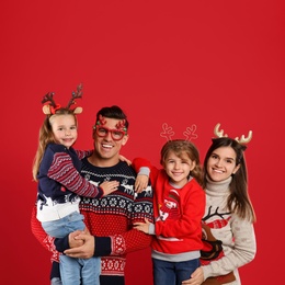 Photo of Family in Christmas sweaters and festive accessories on red background