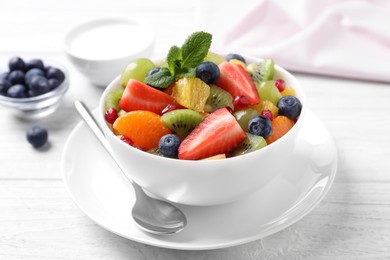 Photo of Delicious fresh fruit salad in bowl on white wooden table