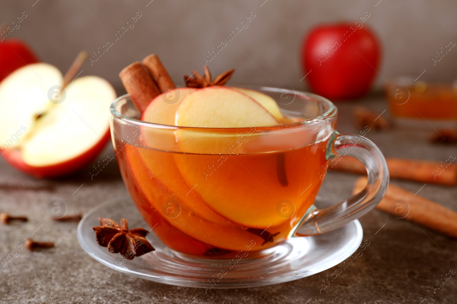 Photo of Aromatic hot mulled cider on grey table, closeup