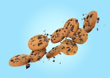 Image of Tasty chocolate chip cookies falling on light blue background