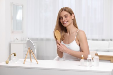 Beautiful woman brushing her hair at vanity in bedroom