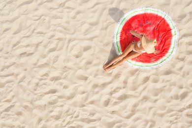 Woman sunbathing on round beach towel at sandy coast, aerial view. Space for text
