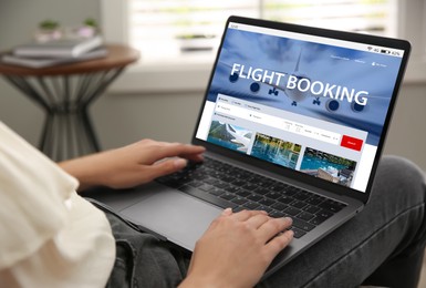 Woman using laptop to book flight at home, closeup