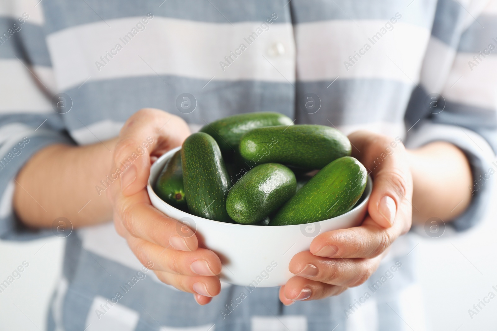 Photo of Woman holding white ceramic bowl with fresh seedless avocados, closeup