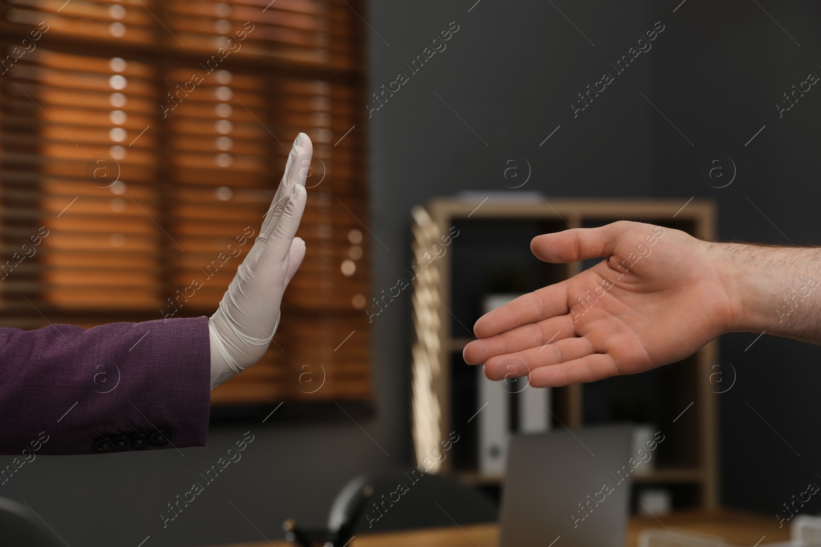 Photo of Woman refusing handshake from coworker at workplace, closeup