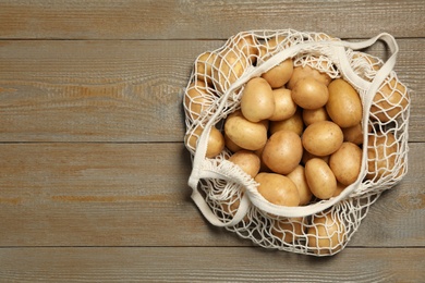 Photo of Raw fresh organic potatoes on wooden background, top view. Space for text