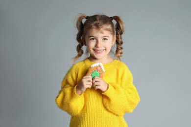 Photo of Cute little girl with Christmas gingerbread cookie on light grey background