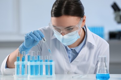 Scientist dripping liquid from pipette into test tube in laboratory