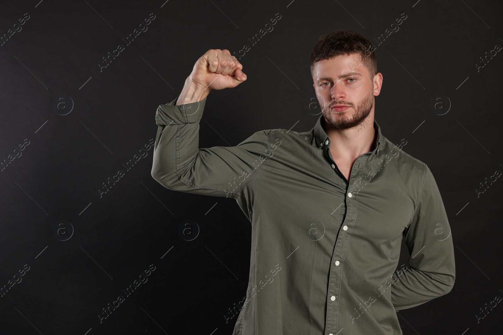 Photo of Young man showing arm on black background, space for text