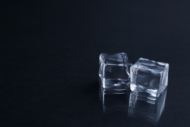 Photo of Crystal clear ice cubes on black background. Space for text