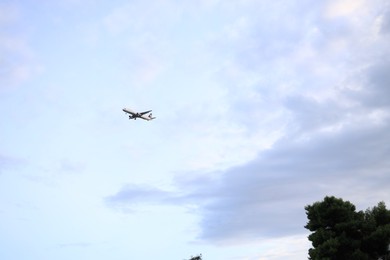 Modern airplane flying in blue cloudy sky. Space for text