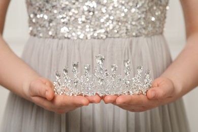 Photo of Woman holding luxurious tiara on grey background, closeup view